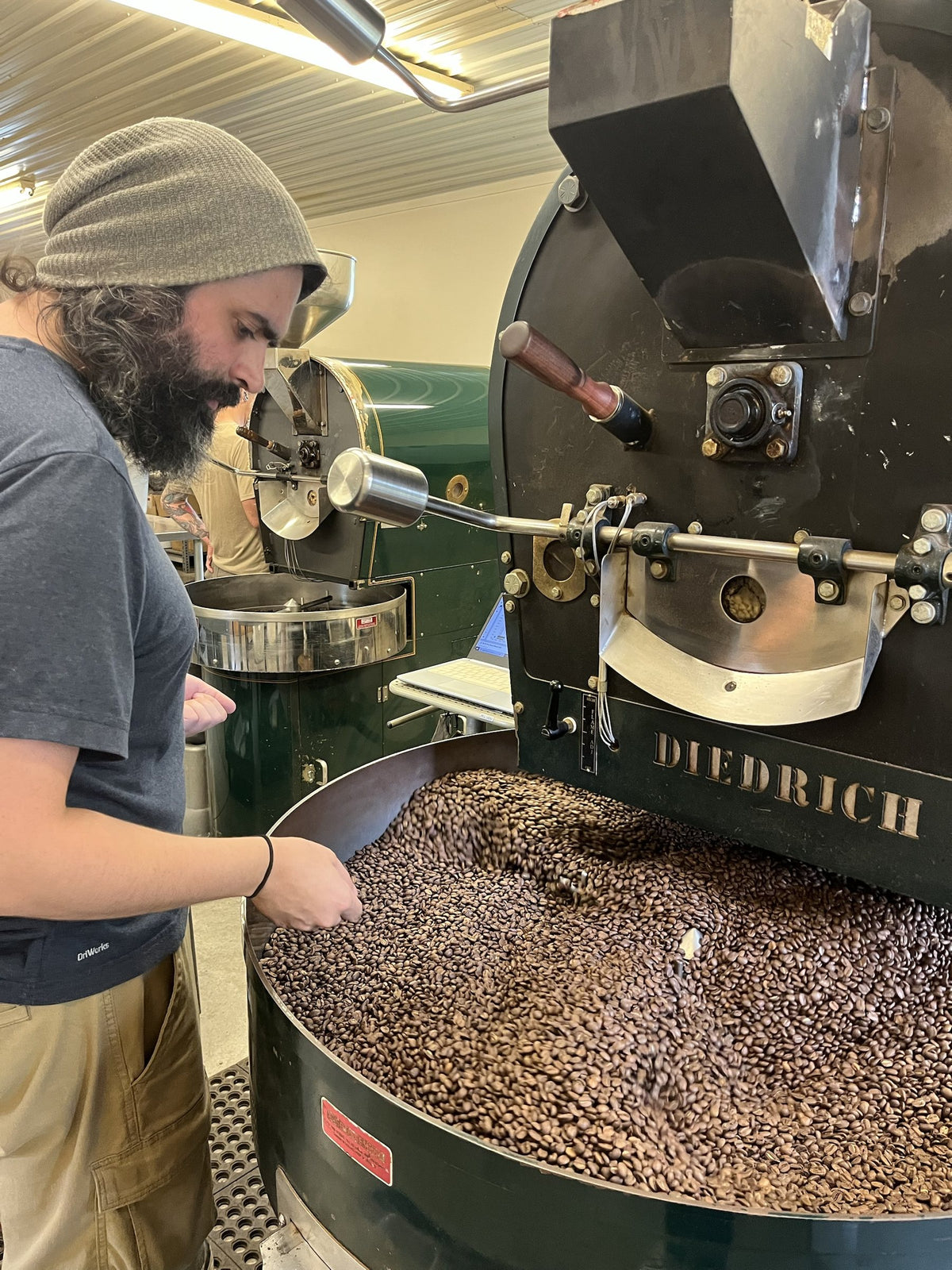 Roaster checking a fresh batch in the cooling tray of the Diedrich roaster
