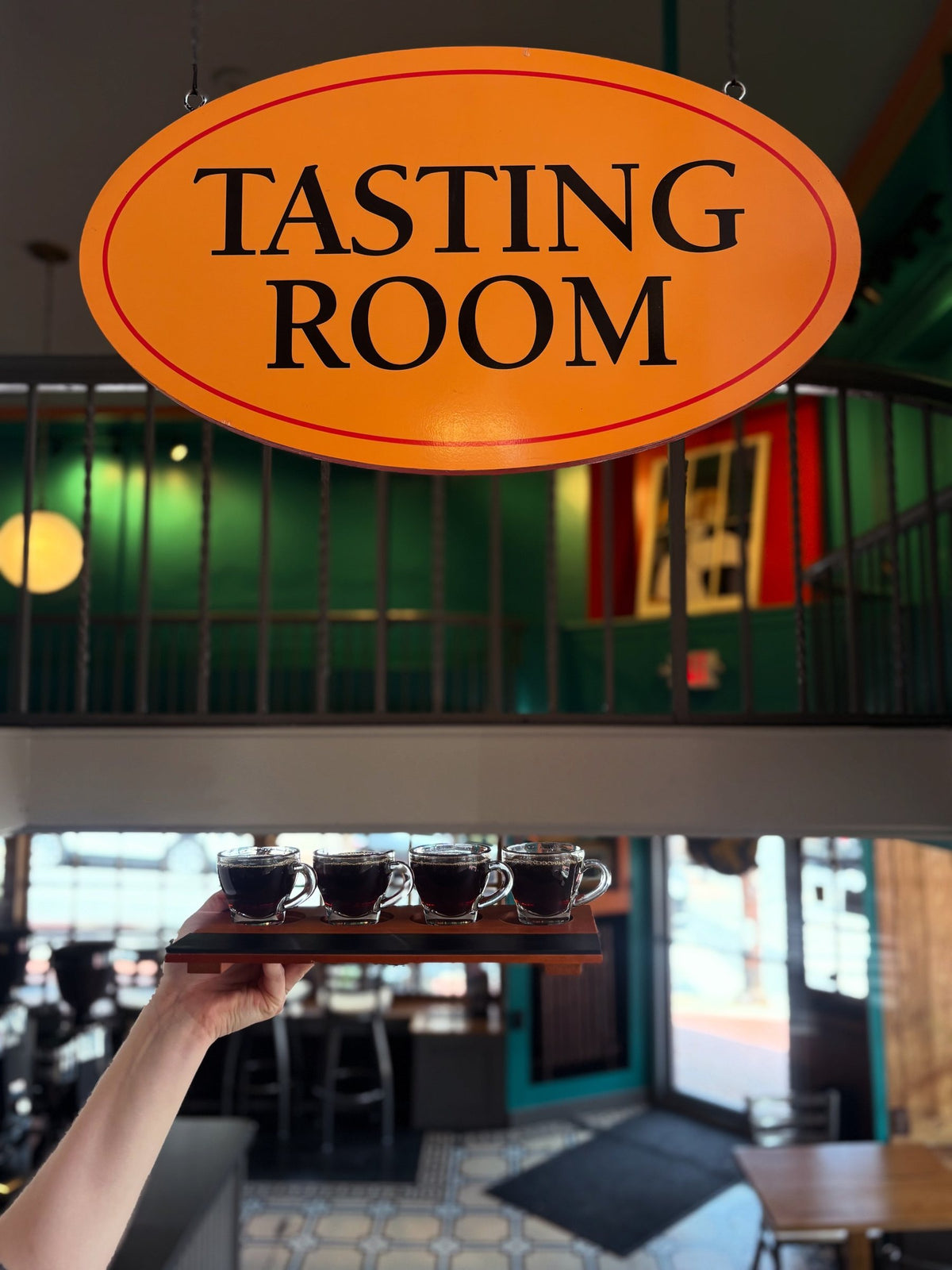 A tasting flight held up under the Tasting Room sign at Hyperion Espresso